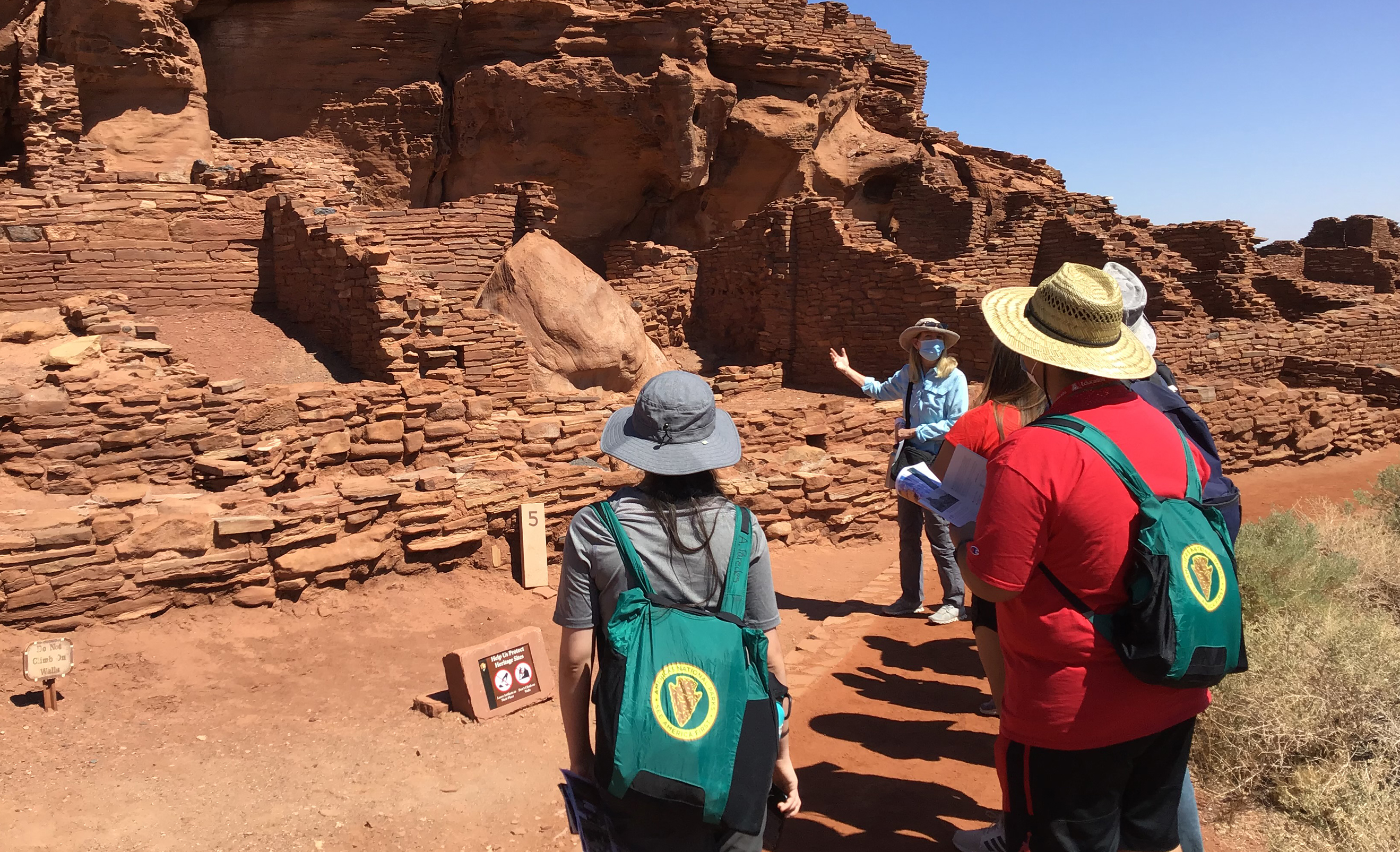 guide showing a group of on lookers cultural ruins in desert setting